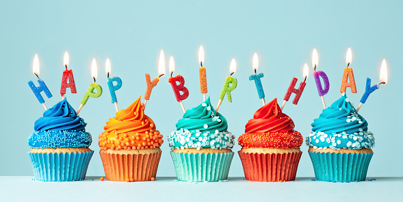 row-of-orange-and-blue-birthday-cupcakes-picture-id1308886360