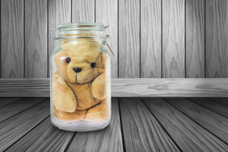 close-up-teddy-bear-glass-jar-gray-wood-background-99260527.jpg